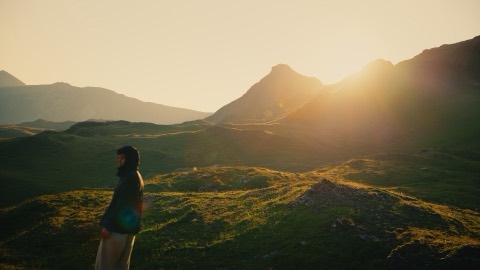 Hillside at sunrise, sun flare behind the ridge, graded with the Alpine Gold LUT