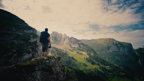 Hiker on a rocky outcrop above the valley, graded with the Alpine Gold LUT