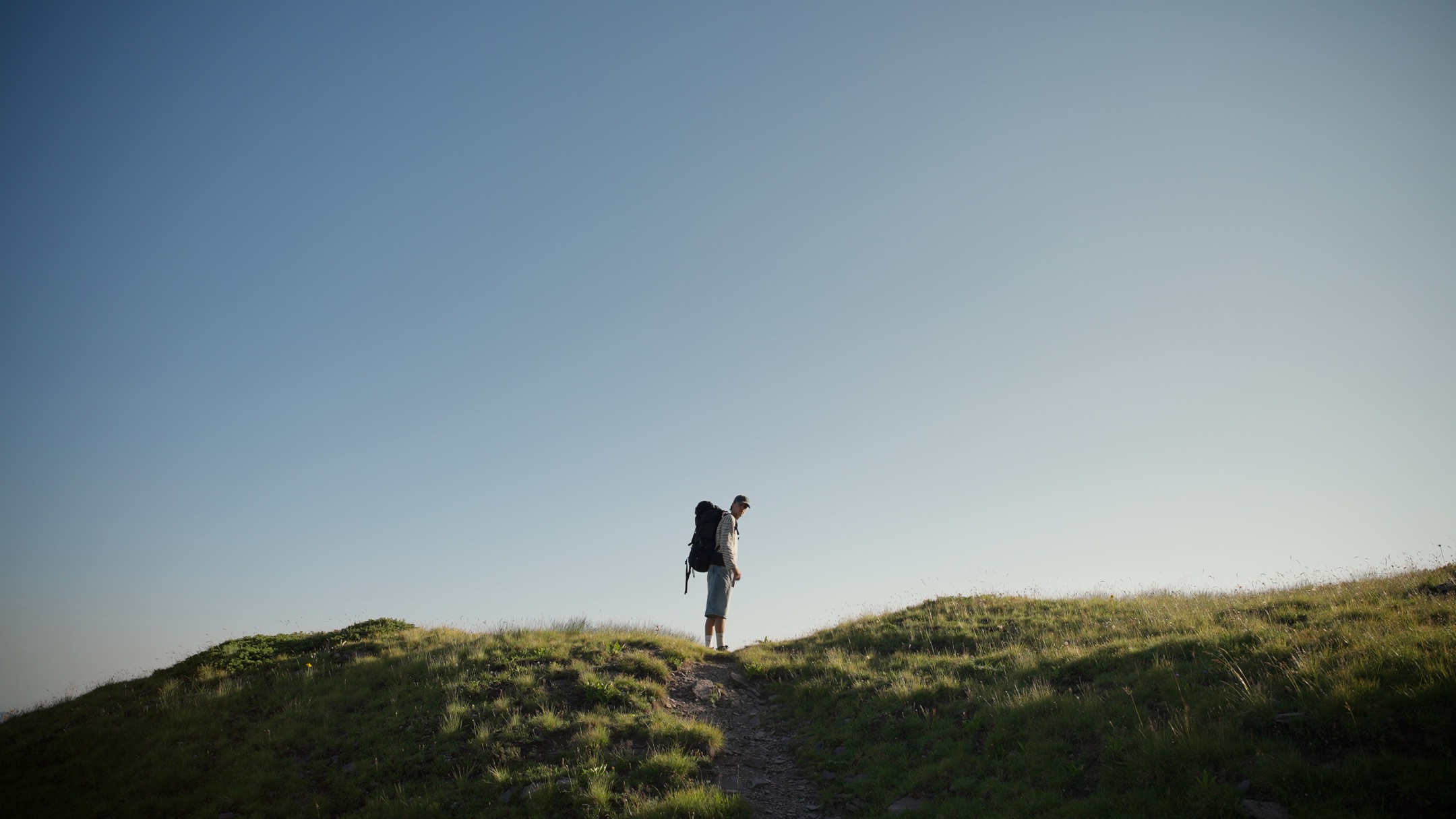 Ungraded Rec.709 frame, lone hiker on a ridge against a deep blue sky